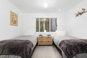 2 Betten in einem weißen Zimmer mit Fenster in der Unterkunft 24 Hyam Rd Hyams Beach in Hyams Beach