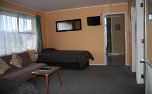 a living room with a couch and a bed at Kuirau Park Motor Lodge in Rotorua