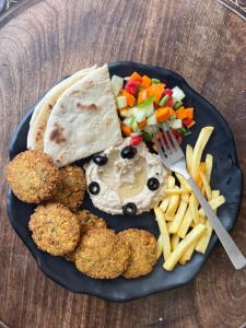un plato de comida con nuggets de pollo y papas fritas en Wabi Sabi Riverside Hostel en Kasol