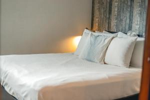 una camera da letto con letto, lenzuola e cuscini bianchi di ARMONIA 408 APARTMENT IN GAZCUE a Santo Domingo
