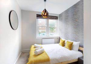 a bedroom with a white bed with yellow pillows at Modern 2 bedroom flat in Hampstead Heath in London