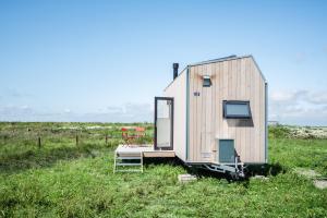 a tiny house sitting in a field of grass at Tiny House Pioneer 18 Zur Meerseite - Green Tiny Village Harlesiel in Carolinensiel