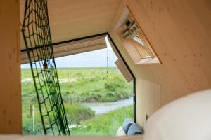 una ventana en una casa pequeña mirando hacia un campo en Tiny House Pioneer 19 Zur Meerseite - Green Tiny Village Harlesiel en Carolinensiel