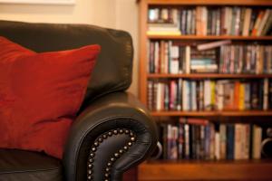 a black chair with a red pillow next to a book shelf at Browns Boutique Hotel in Queenstown