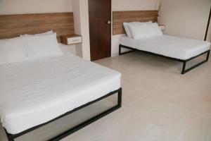 a bedroom with two beds with white sheets at Hotel Fratelli in Aguascalientes