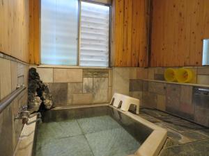 a bath tub in a room with a window at Hakone Miyanoshita Myojokan in Hakone