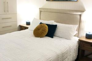Dolphin Shores في Corlette: غرفة نوم عليها سرير ابيض ومخدة صفراء