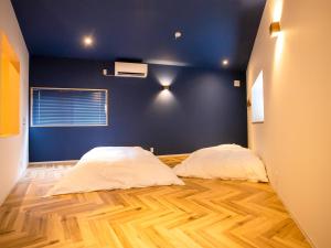two beds in a room with a blue wall at LifeStyleHotel ichi一棟貸切りホテル in Kochi
