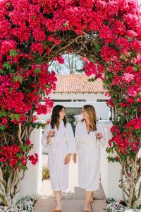 two women in white robes walking under a arch of flowers at Omni La Costa Resort & Spa in Carlsbad