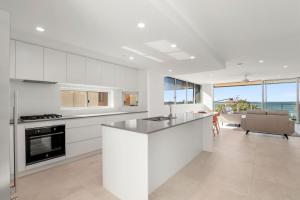 een keuken met witte kasten en een aanrecht bij Kings Surf Unit 6 5 Ormonde Tce Kings Beach in Caloundra