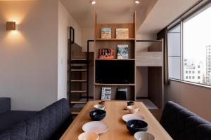a living room with a wooden table and a tv at COCOSHUKU Asakusa Kuramae in Tokyo