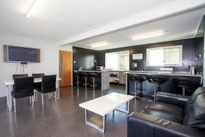 a living room with black leather furniture and a bar at Mycow Accommodation Mackay in Mackay