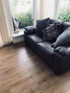 um sofá de couro preto num quarto com uma janela em Highfield Road Apartment. em Rowley Regis