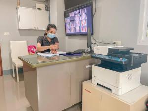 a woman is sitting at a desk with a mask on at OYO 75403 Dinosaur Apartment in Hua Hin