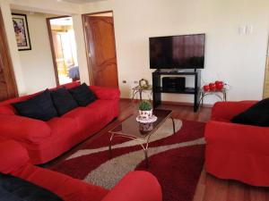 een woonkamer met rode banken en een flatscreen-tv bij Departamento REKADI in Cuzco