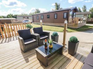 a deck with two chairs and a bottle of wine on it at Langdale Lodge in Carnforth