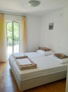 two beds in a white room with a window at Apartman Zrina Oštro in Kraljevica