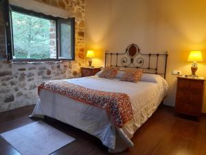 1 dormitorio con 1 cama grande, 2 lámparas y ventana en Apartamentos Rurales Larrago, en Busturia