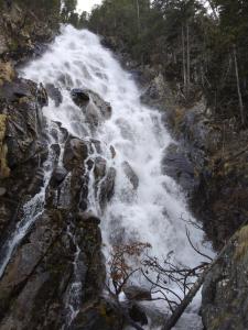 una cascada a un lado de una montaña rocosa en APARTAMENTS CASA NANDO., en Esterri d'Àneu