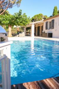 einen Pool mit blauem Wasser vor einem Haus in der Unterkunft Villa Petit Paradis - Gigaro in La Croix-Valmer