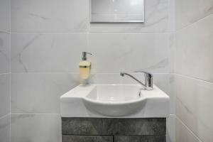 a white sink in a white tiled bathroom at Boutique Maisonette in Pefkohori