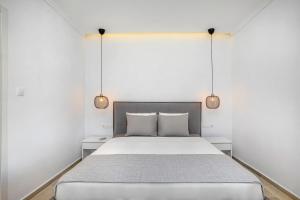 a bedroom with a large bed with two lights at Boutique Maisonette in Pefkohori +18 photos