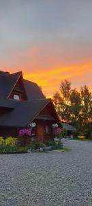 a house with a roof with a sunset in the background at Chata Leona in Gorlice