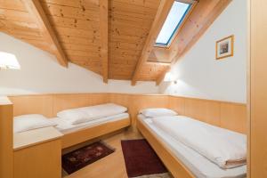 Habitación pequeña con 2 camas y techos de madera. en Residence Chalet Pinis, en Corvara in Badia