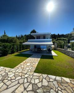una casa con una pasarela de piedra frente a un edificio en Villas Vento Lefkada, en Agios Nikitas