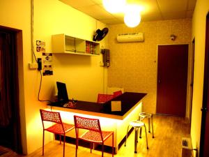 a kitchen with a bar with chairs and a desk at Fang Zu Ming Concept Guesthouse in Ayer Itam