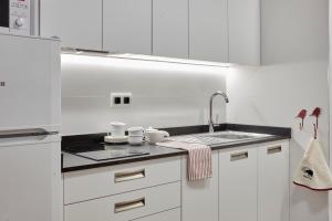 una cocina blanca con armarios blancos y fregadero en Apartamentos Ea Astei, en Ea