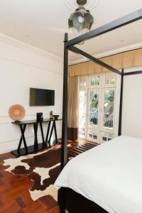 1 dormitorio con 1 cama y TV en la pared en The Winston Hotel, en Johannesburgo