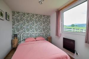 a bedroom with a pink bed and a window at Sarnia Łąka domek z prywatnym jacuzzi in Stronie Śląskie