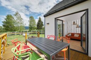 a patio with a table and chairs on a deck at Sarnia Łąka Domek 2 z opcją prywatnego jacuzzi in Stronie Śląskie