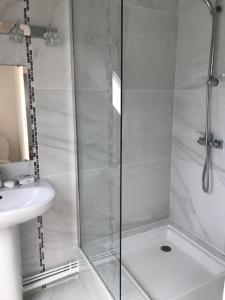 uma casa de banho branca com um chuveiro e um lavatório. em Maison moderne 8 personnes, jardin, parkings, fibre THD, plage 5 min em Vannes