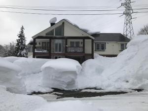 a house covered in snow in front of a house at Legend Inn Myoko in Myoko