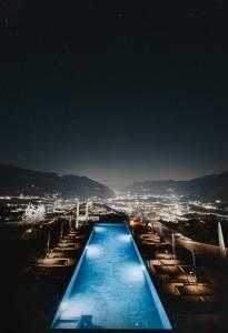a swimming pool with chairs and a city at night at La Vista Nature Living in Tirolo