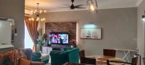 a living room with green chairs and a tv at # Free Netflix CMK KONDOMINIUM KOTA SRI MUTIARA in Kota Bharu