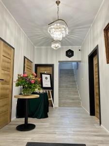 a hallway with a table with flowers and a chandelier at Capitals Residence in Oświęcim