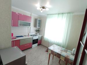a small kitchen with pink cabinets and a table at Апартаменты 11 мкрн-3 in Aktobe