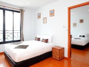 two beds in a white room with a window at Double DD House at MRT Sutthisarn in Bangkok