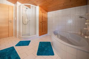 a bathroom with a tub and a shower and blue rugs at Appartment Lechner in Neukirchen am Großvenediger +17 photos