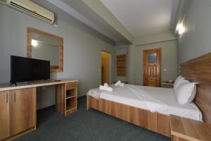 Hotel Cora في كونستانتا: غرفة نوم بها سرير وتلفزيون ومكتب