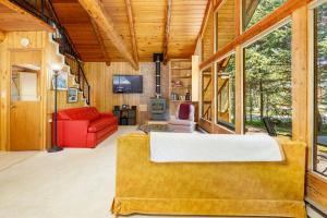 sala de estar con sofá rojo y ventanas en Alpine Meadows Log Cabin, en Girdwood