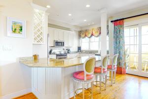 a kitchen with white cabinets and a counter with stools at Sunset Island - Beachside Mews 1 & 2 in Ocean City