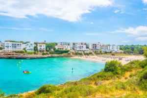 ein Strand mit einer Gruppe von Gebäuden und Menschen im Wasser in der Unterkunft La Ola Beach House in Portocolom
