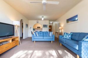 a living room with two blue couches and a flat screen tv at Seahorse 4 in Tuncurry