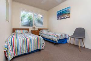 a bedroom with two beds and a chair in it at Seahorse 4 in Tuncurry