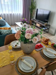 a table with plates and a vase of flowers on it at Hubane Olevi Apartment in Võru
