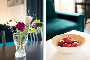 eine Vase mit Blumen und eine Schale mit Äpfeln auf dem Tisch in der Unterkunft L.E. Home II in Leipzig